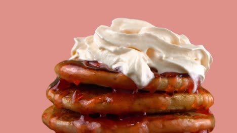 american pancakes with strawberry topping and whipped cream. on a pink background.