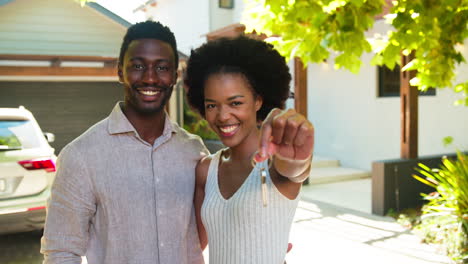 portrait of couple outdoors holding keys to dream home