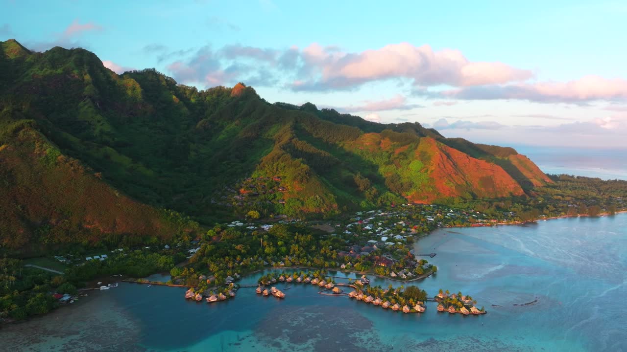 Golden hour sunny sunset water bungalows Cooks Opunohu Bay Moorea island French Polynesia aerial drone Mount Mauaroa Tohivea Rotui clouds boats lagoon coral reef waves Pacific Ocean backwards pan up