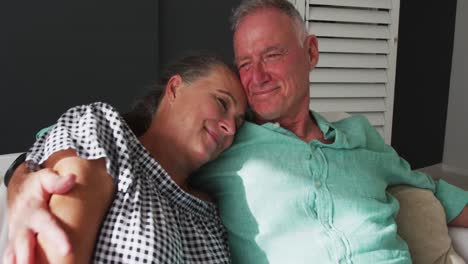 Caucasian-senior-couple-hugging-each-other-while-sitting-on-the-couch-at-home