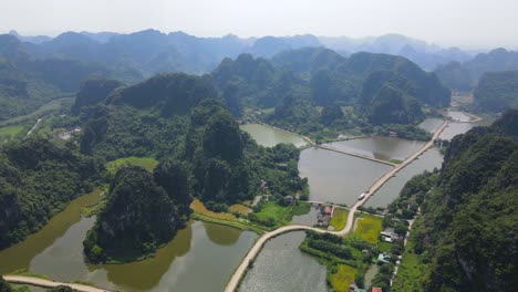 drone shot of zig zag road between lakes and limestone mountain range ninh binh viet nam