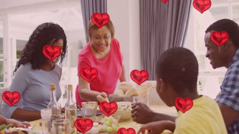 red hearts animation over family enjoying meal together at dining table