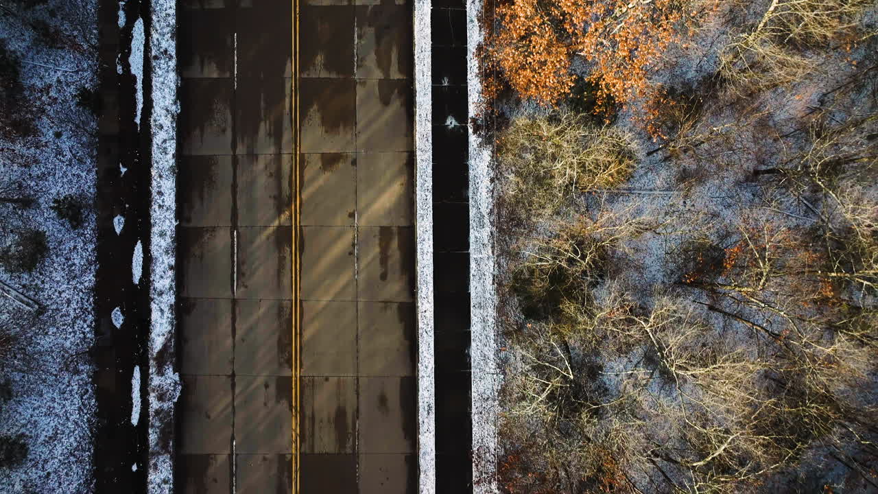 Aerial shot of Mount Sequoyah, AR with a wide street and autumn trees, sunlight casting shadows