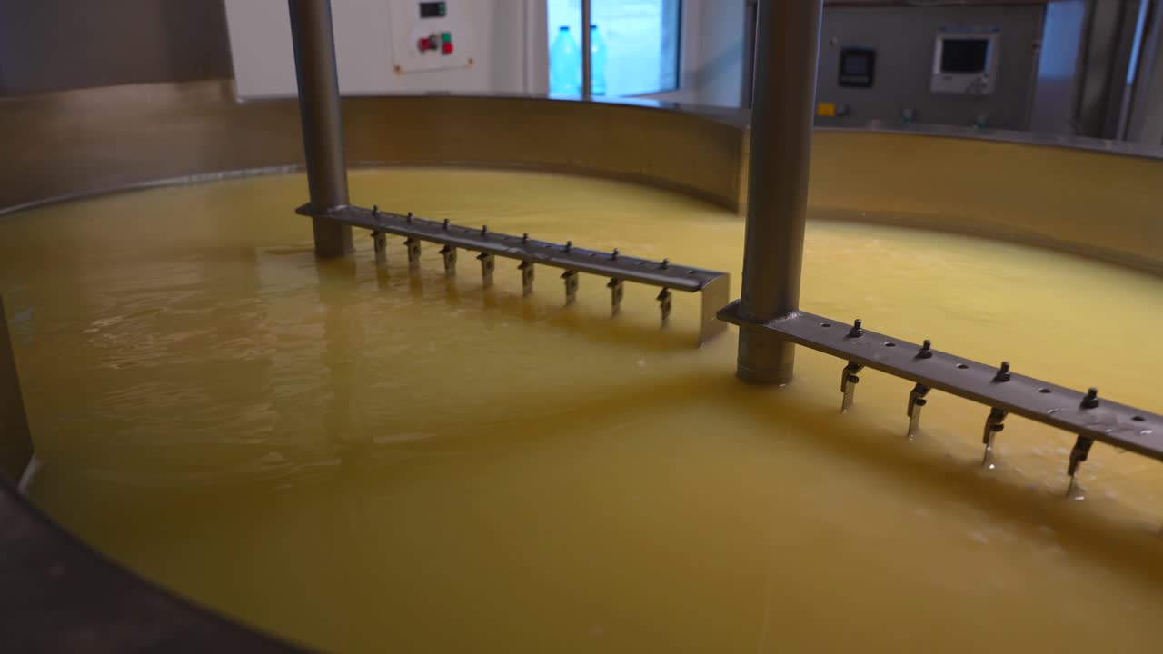 Machines mixing milk in curd preparation tank at cheese factory