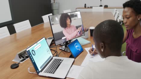 Diverse-businesswomen-in-office-using-computer-with-video-call-and-ai-messaging-on-screens