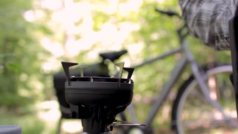 fahrradperson, die kaffee über einem campinggasherd im sommerwald kocht