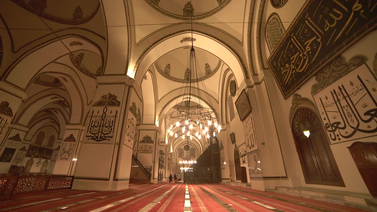Interno di una grande moschea con architettura riccamente decorata.