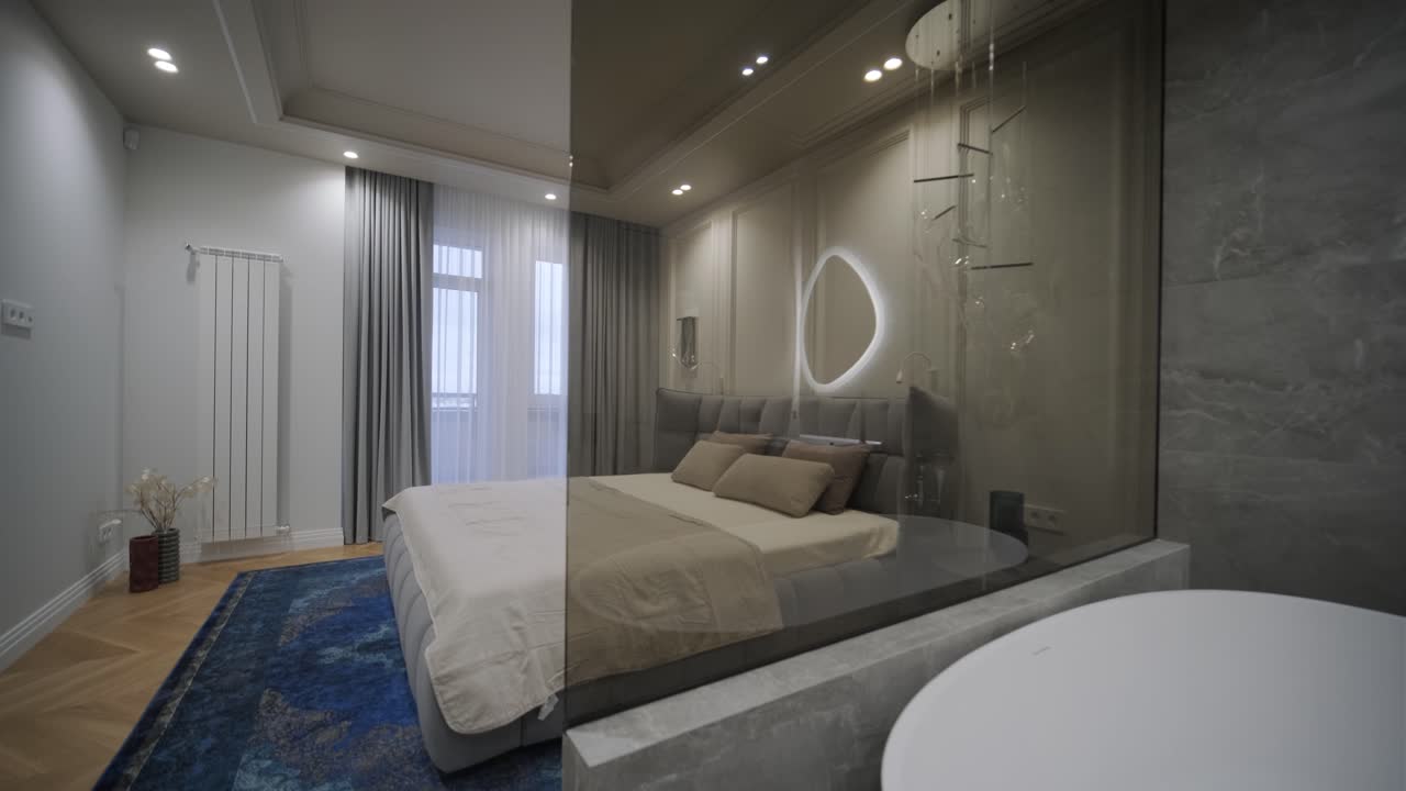 Luxurious bedroom with a tufted headboard and integrated bathroom featuring a freestanding bathtub and illuminated mirror