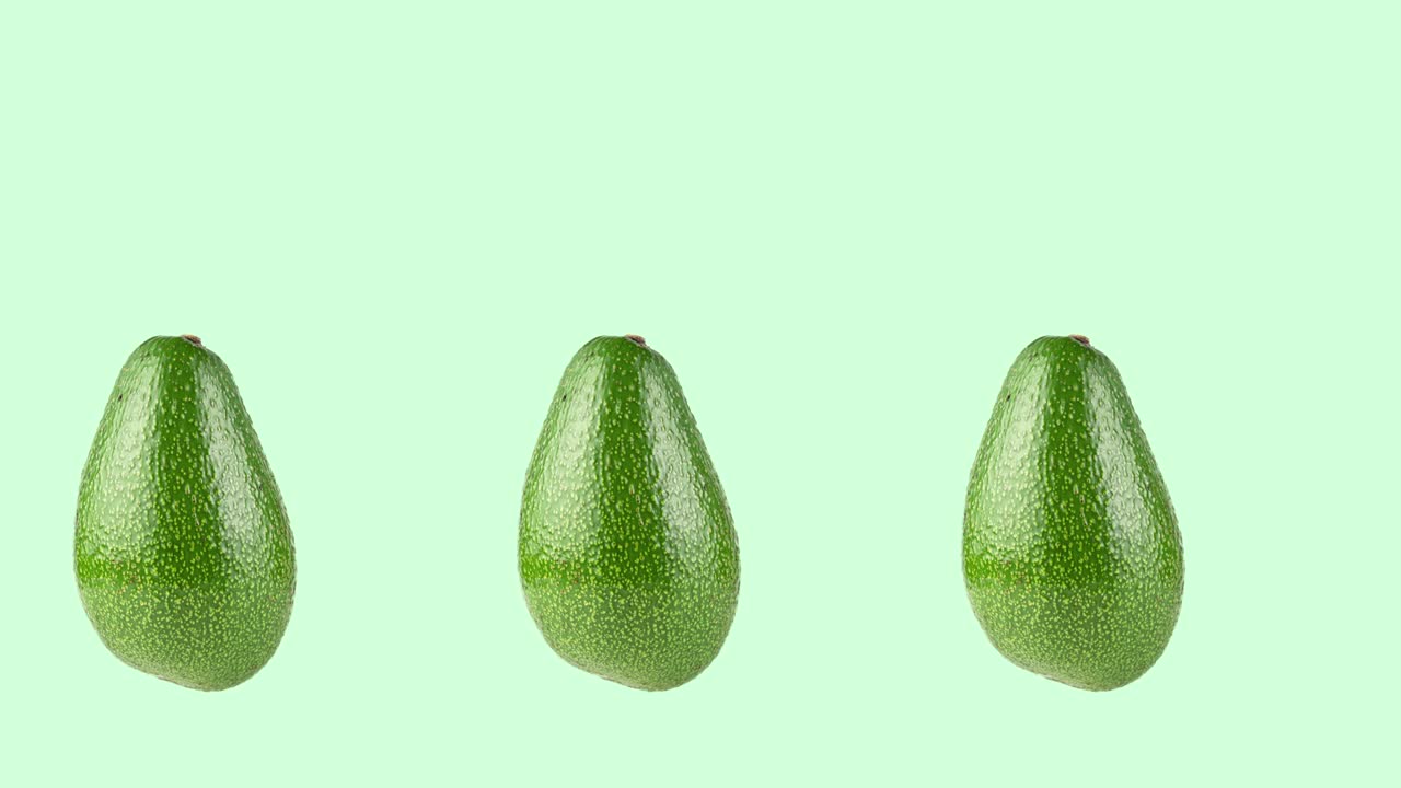 many whole avocados rotating close-up on a green background. seamless looping animation with copy space