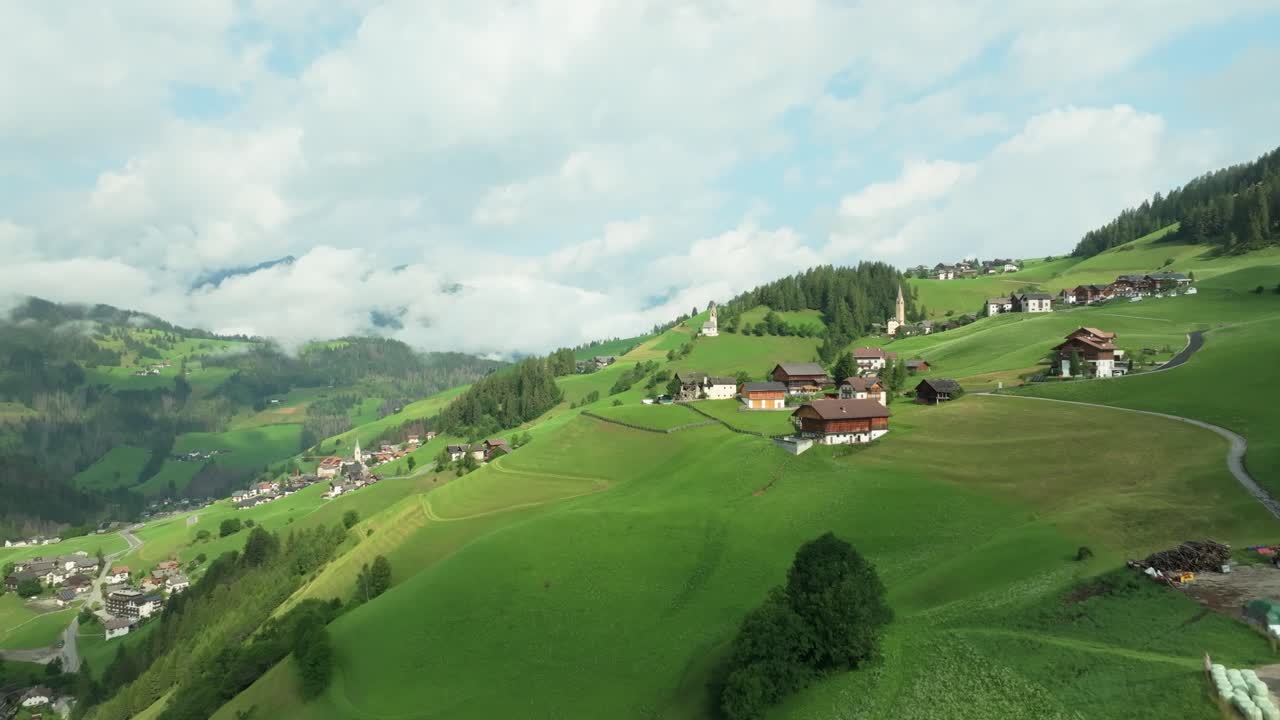 Flying above lush greenery towards a church on the steep slopes of the village of La Va, South Tyrol, Italy