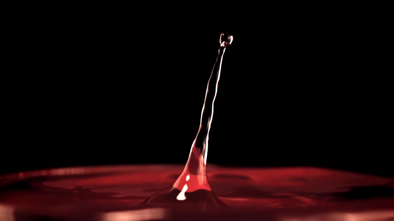 Goccia di liquido rosso al rallentatore che schizza e crea una corona.