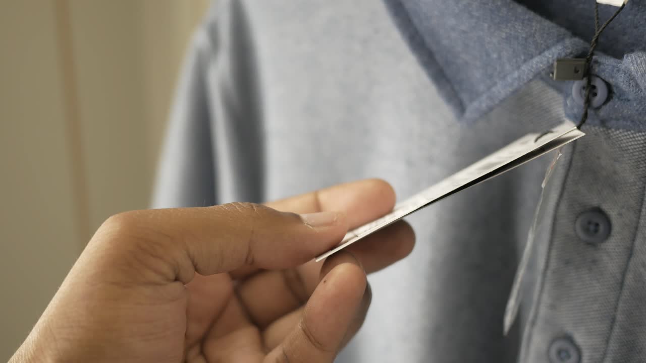 persona con una etiqueta de precio en una camiseta polo