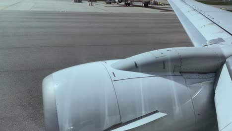 Airplane-Wing-And-Engine-Moving-On-The-Airport-Runway-in-Porto-Portugal,-Europe--Tracking-Shot