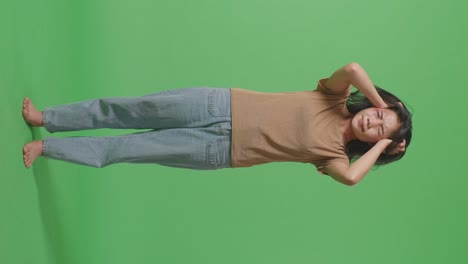 젊은 아시아 여성이 폭력의 희생자로 몸에 이 있고 신경 붕괴를 겪고 녹색 스크린 배경 스튜디오에서 비명을 지르고 있습니다.