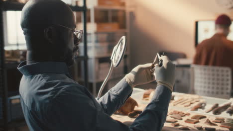 black archaeologist examining artifact with caliper in laboratory