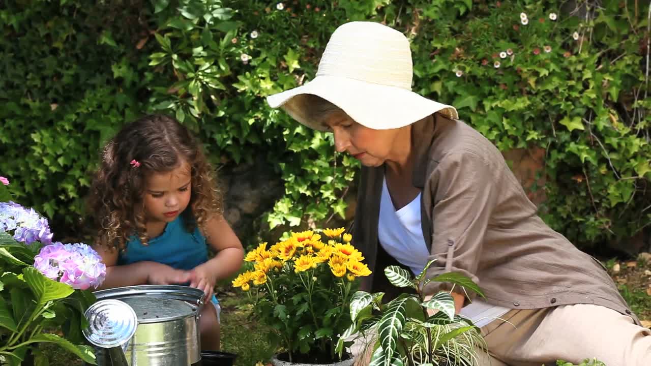 Mujer mayor y un niño cuidando el jardín