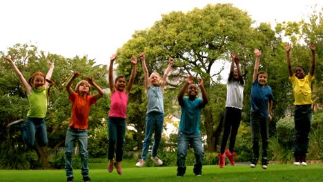 Süße-Schüler-Springen-Auf-Dem-Rasen-Vor-Der-Schule