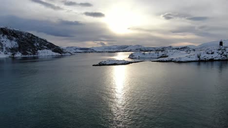 drone view in tromso area in winter flying over a snowy islands surrounded by the sea in norway