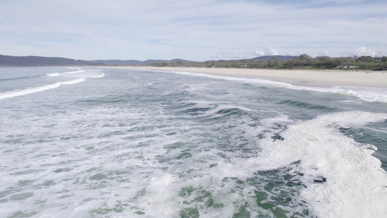 Onde schiumose a Seven Mile Beach - Veicoli in transito su The Lakes Way vicino al lago Wallis a Forster, Nuovo Galles del Sud, Australia