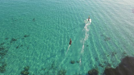 aerial view of two tourists driving jet skies in the blue water of cala escondida, spain