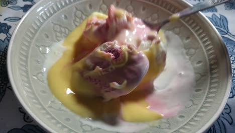 노란색 바닐라 커스터드 토핑을 곁들인 딸기, 바닐라, 검은색 현재 맛 아이스크림, 맛있는 일요일 디저트는 도자기 그릇에 스테인리스 스틸 스푼으로 퍼집니다.