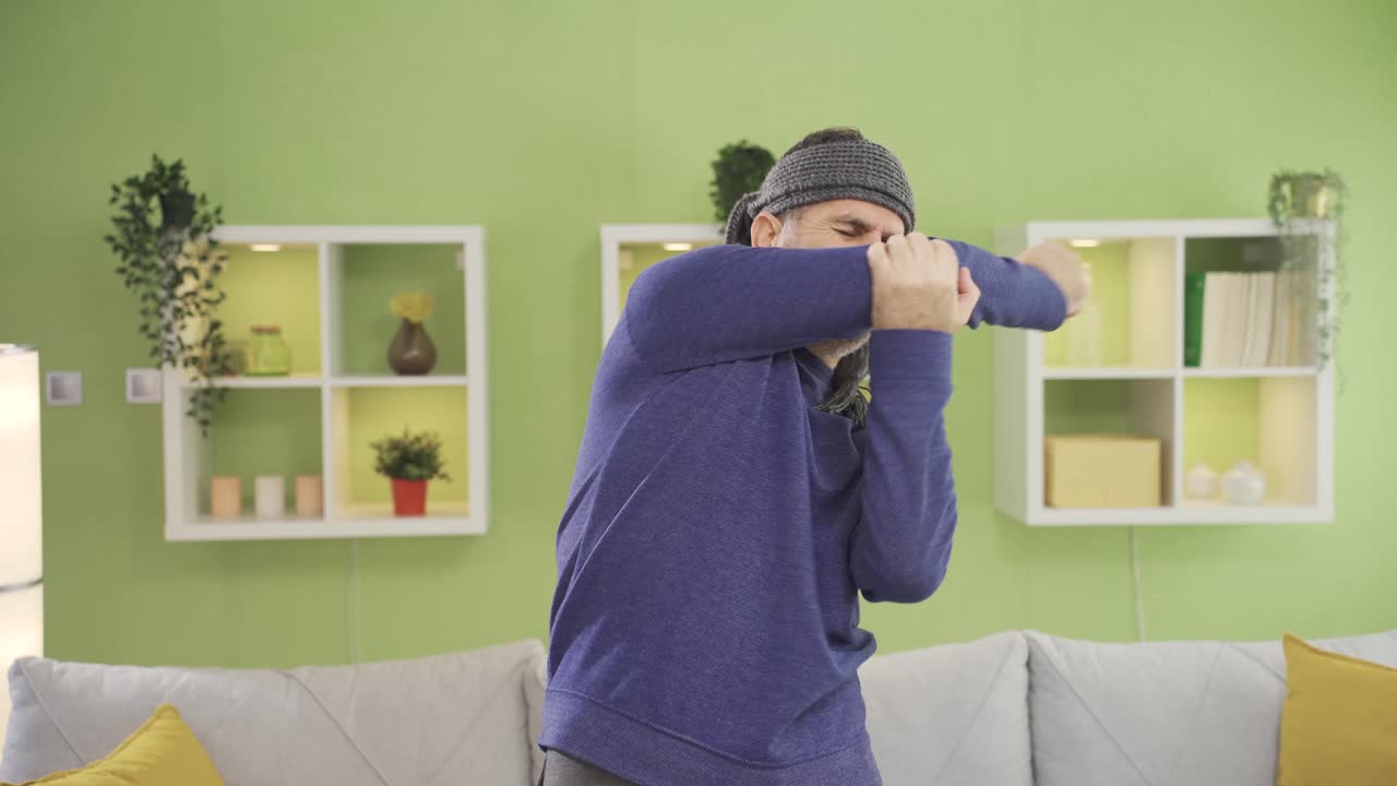 성숙한 남자가 집에서 스포츠를 하면서 팔과 어깨를 다쳤습니다.