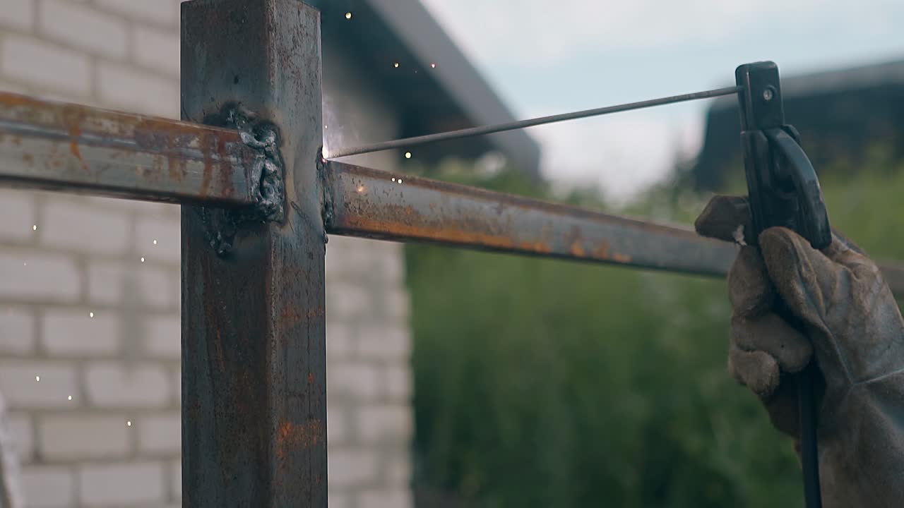 밤에 금속 울타리를 용접하는 느린 움직임의 클로즈업 작업자