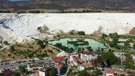 Impresionante-Vista-Aérea-De-Un-Lago-Azul-Rodeado-De-Terrazas-Montañosas-Ricas-En-Minerales-Blancos-Llenas-De-Piscinas-Termales-En-Pamukkale,-Turquía