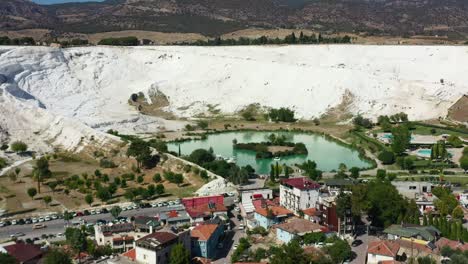 impresionante vista aérea de un lago azul rodeado de terrazas montañosas ricas en minerales blancos llenas de piscinas termales en pamukkale, turquía