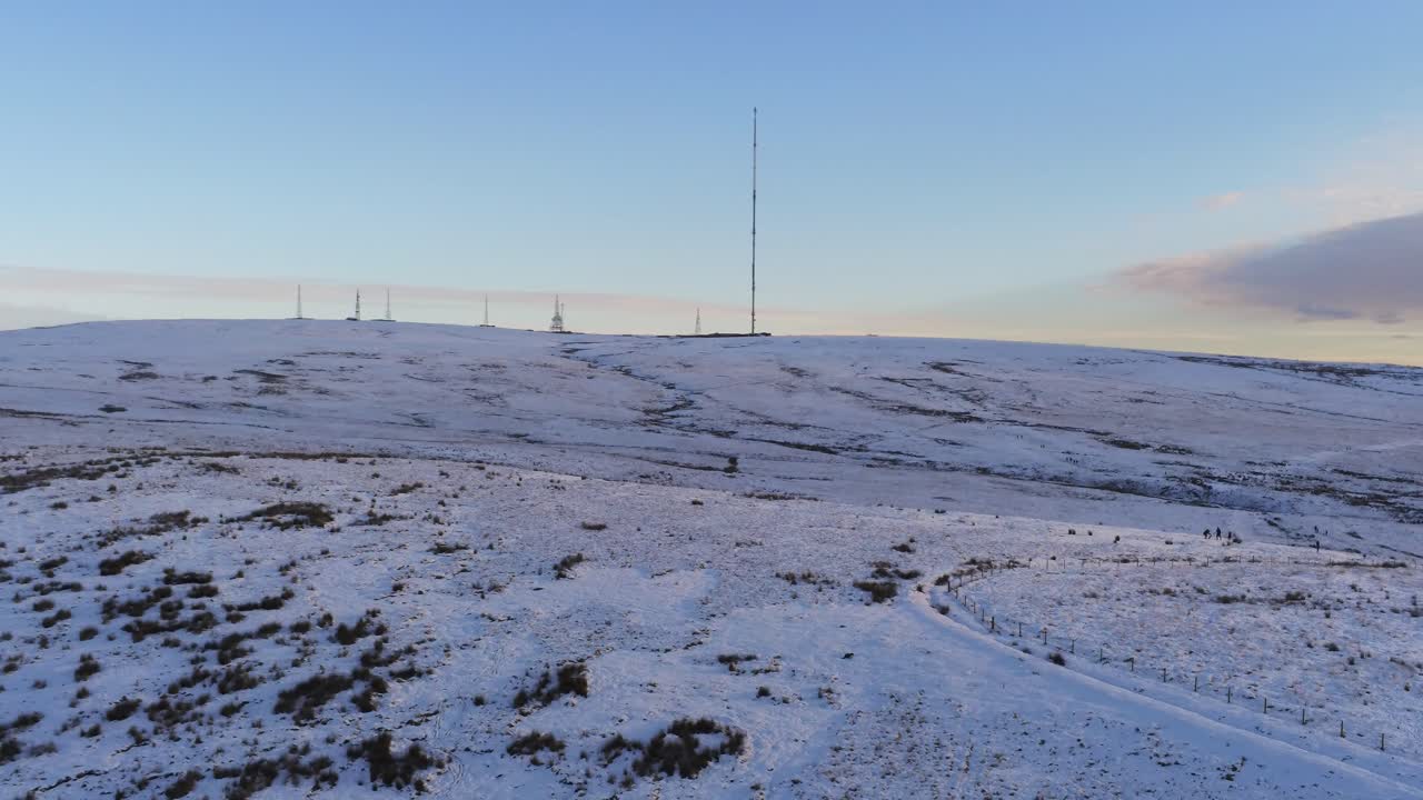 Drone view Winter hill snowy rural broadcast antenna signal towers on Lancashire West Pennine moors slow pan right