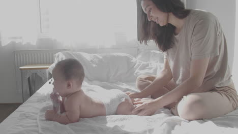 mamá feliz cuidando a su lindo bebé en el dormitorio