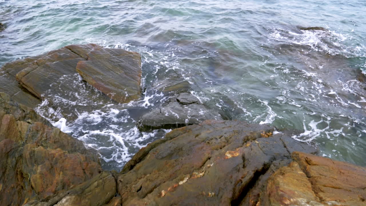 Paesaggio panoramico al rallentatore della costa con onde marine che si infrangono sulla spiaggia con sassi e rocce, concetto di vacanza estiva