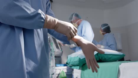 diversos cirujanos masculinos y femeninos con máscaras faciales usando guantes médicos en cámara lenta, sin alteración.