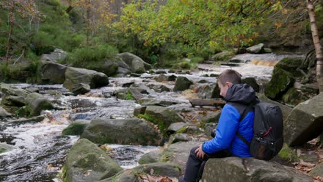 Young-boy,-camera-and-tripod,-captures-serene-autumn-winter-woodland,-meandering-stream