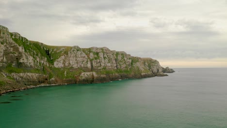 Zoom-in-aerial-shot-of-cliffs-along-the-coast-in-New-Zealand-during-sunset