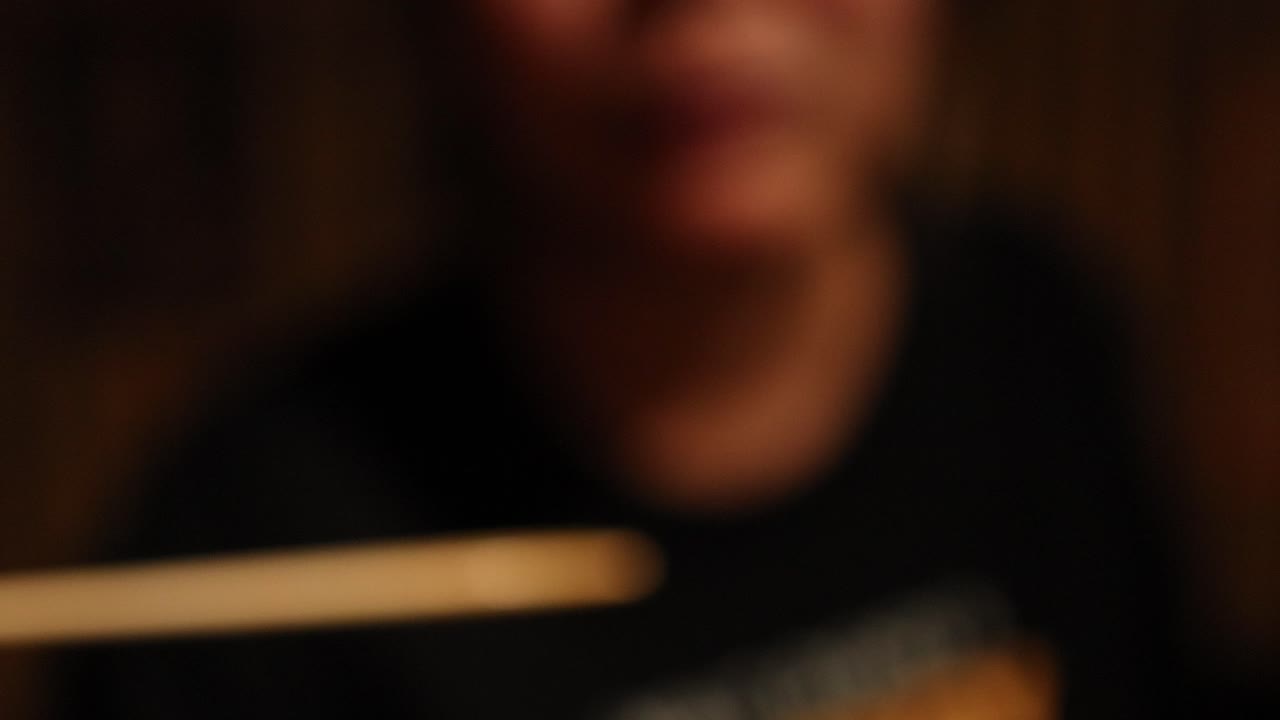 Person eating with chopsticks in blurred focus