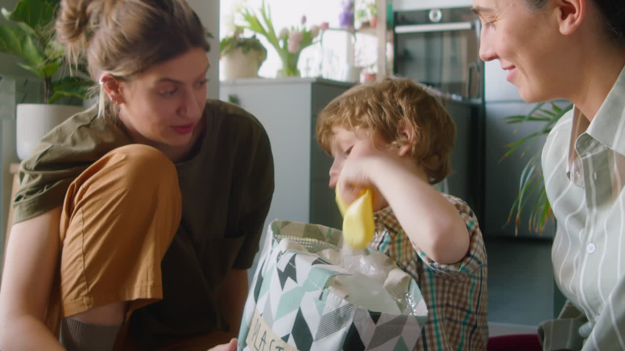 Little Boy Helping Lesbian Parents with Sorting Plastic Waste at Home