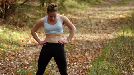 Young-atletic-woman-runner-warming-up-before-workout-in-forest