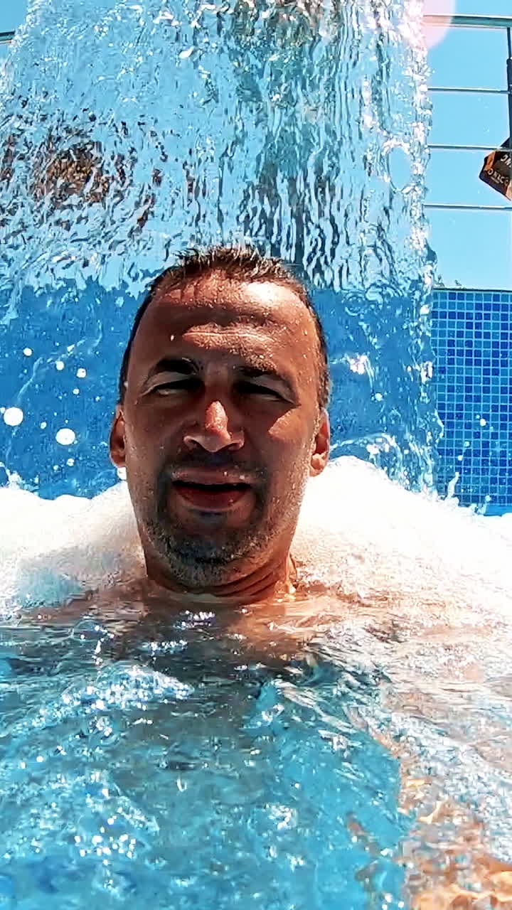Man refreshing on vacation. Selfie shot of man in water surface at pool