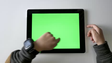 children's hands swiping on a tablet, green screen, chromakey concept, top shot 60 fps