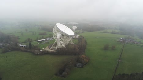 Aerial-Jodrell-bank-observatory-Lovell-telescope-above-misty-rural-countryside-high-pull-back