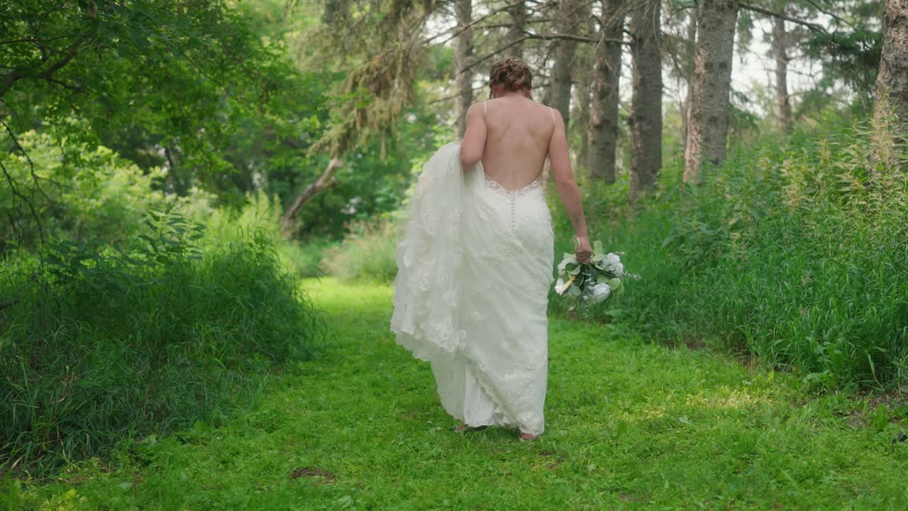 Bride standing in forest shifting back and forth, smiling at camera in wedding dress
