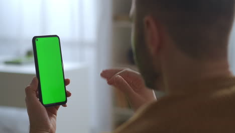 Pantalla-Verde-De-Un-Teléfono-Inteligente-Moderno-En-Manos-De-Un-Hombre-Charlando-Por-Video-Chat-Con-Amigos-O-Colegas-Vista-De-Primer-Plano-Del-Dispositivo-A-Través-Del-Hombro-Masculino