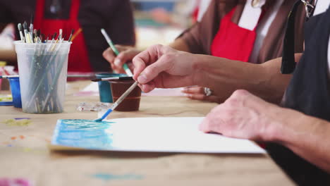 close up of woman attending art class in community centre painting picture