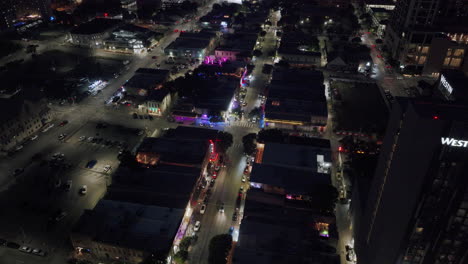 aerial night view of a lively city street with illuminated buildings and traffic
