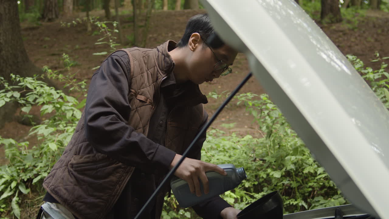 Man changing oil in car in the forest