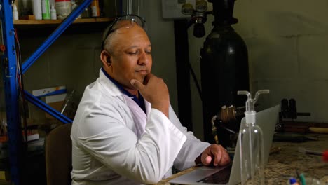 side view of mature male worker using laptop at desk in glass factory 4k