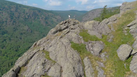 a young woman is sitting on the edge of an impressive mountain cliff