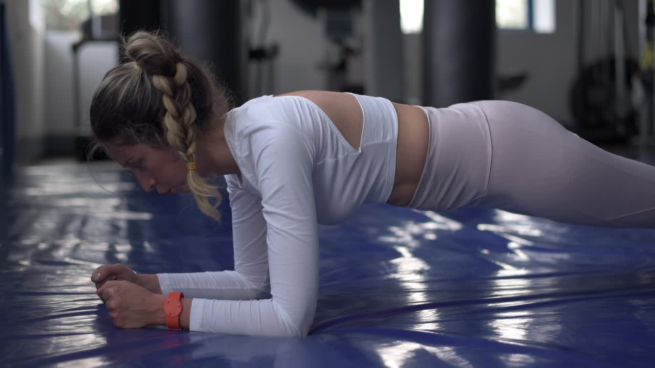 Woman in white and purple activewear holding the plank at the gym