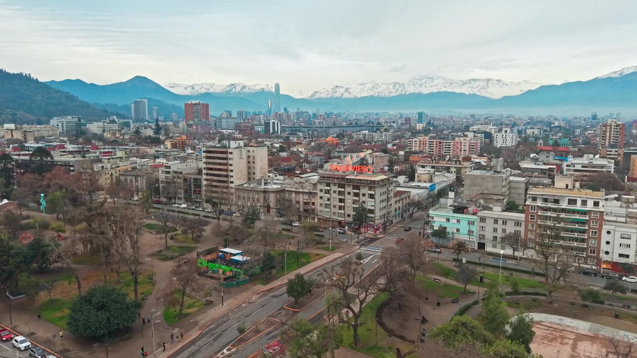 Veduta aerea che mostra il Parco Bustamante e la città di Santiago, Cile, in una giornata nuvolosa, con le montagne innevate sullo sfondo